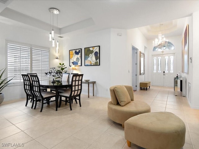 tiled dining area featuring a chandelier and a raised ceiling