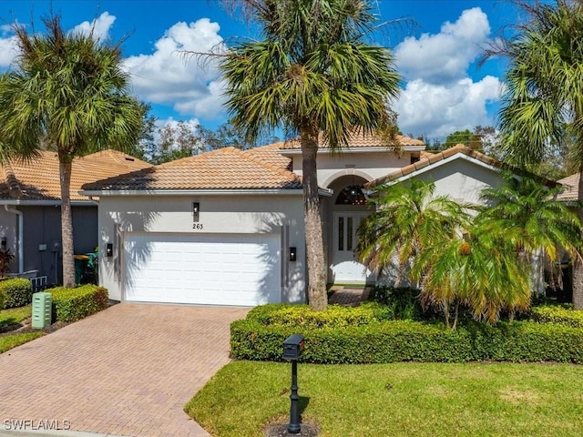 mediterranean / spanish home featuring a garage and a front lawn