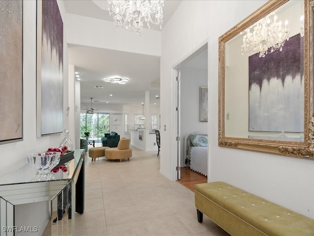 corridor featuring light tile patterned flooring and an inviting chandelier