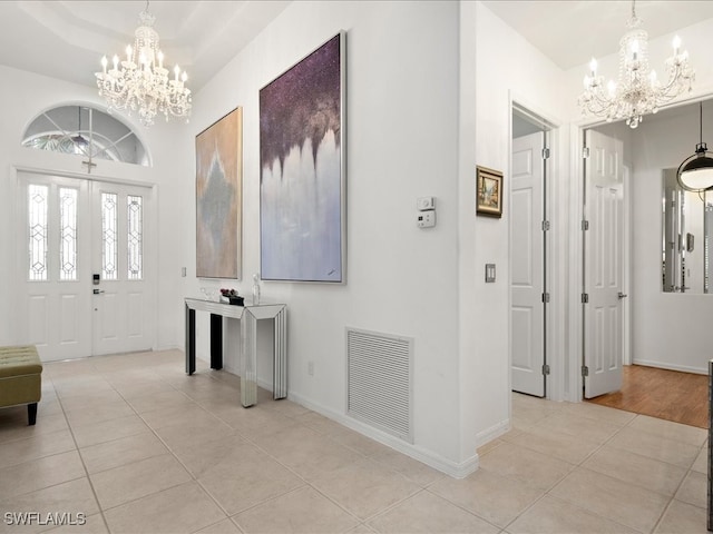 entryway featuring light tile patterned floors, a tray ceiling, and a chandelier