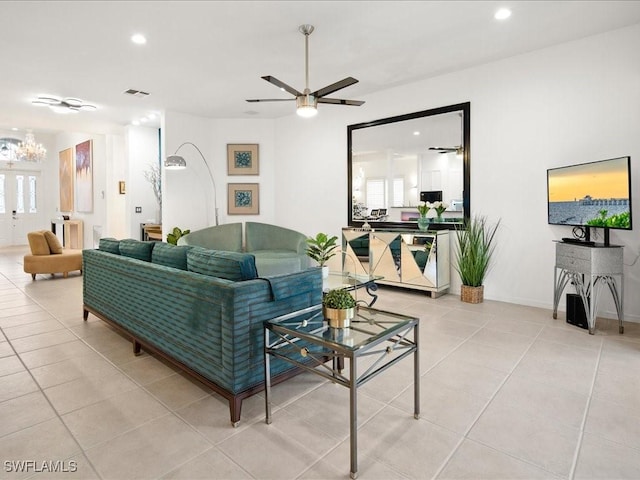 tiled living room with a healthy amount of sunlight and ceiling fan with notable chandelier