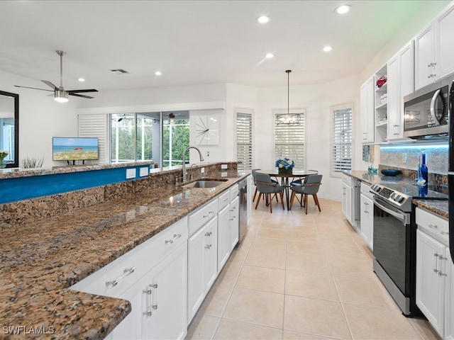 kitchen with stainless steel appliances, white cabinetry, dark stone counters, and sink