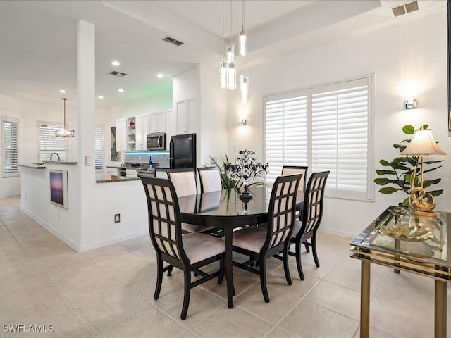 tiled dining area with sink and an inviting chandelier