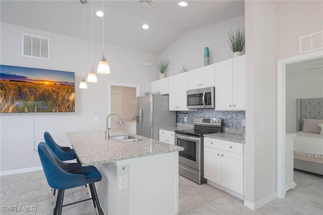 kitchen featuring lofted ceiling, a center island with sink, sink, appliances with stainless steel finishes, and decorative light fixtures