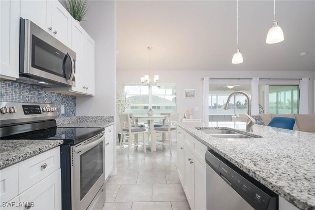 kitchen featuring sink, white cabinets, decorative light fixtures, and appliances with stainless steel finishes