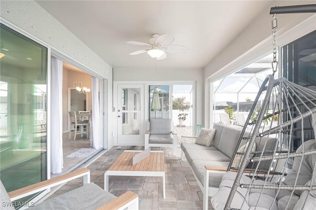 sunroom / solarium featuring ceiling fan with notable chandelier