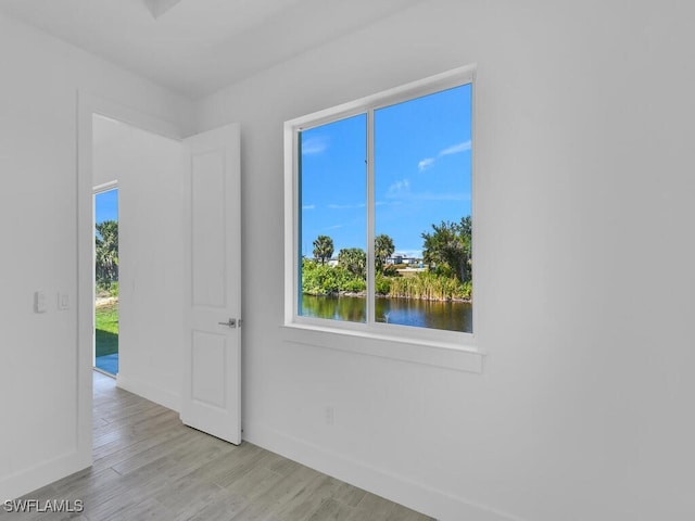 empty room featuring light hardwood / wood-style floors, a water view, and a wealth of natural light