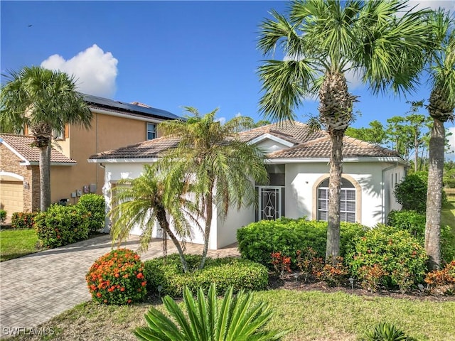 2505 Keystone Lake Dr, Cape Coral, FL 33909 - mediterranean / spanish-style house featuring a tiled roof, decorative driveway, an attached garage, and stucco siding