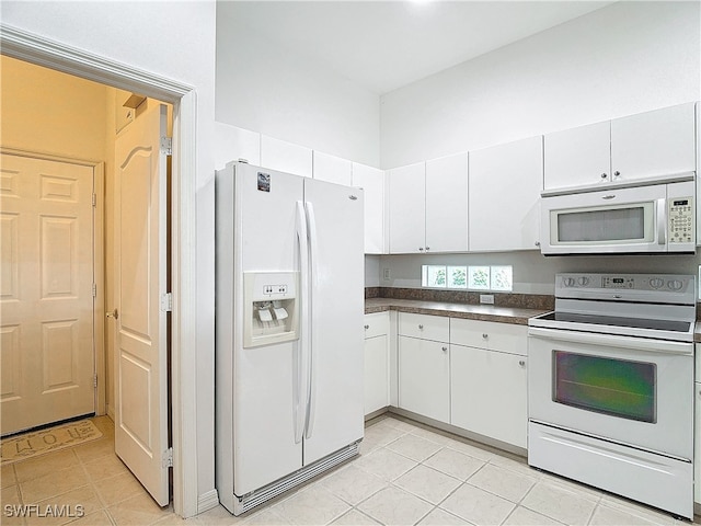 kitchen with white cabinetry, white appliances, and light tile patterned floors