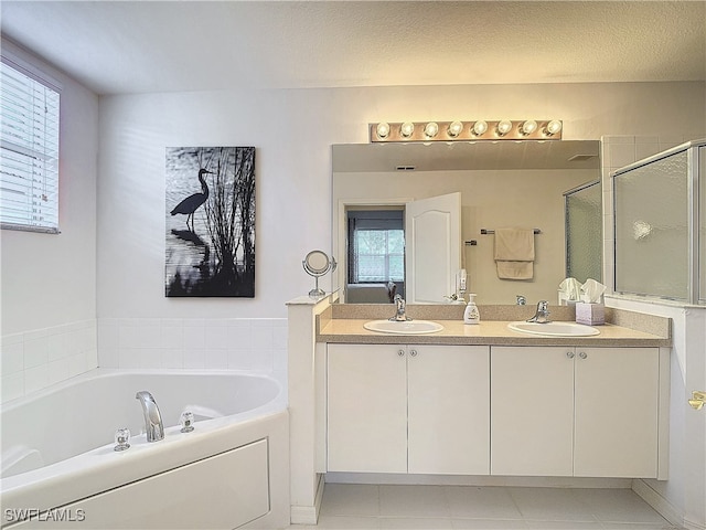 bathroom with vanity, independent shower and bath, a textured ceiling, and a healthy amount of sunlight