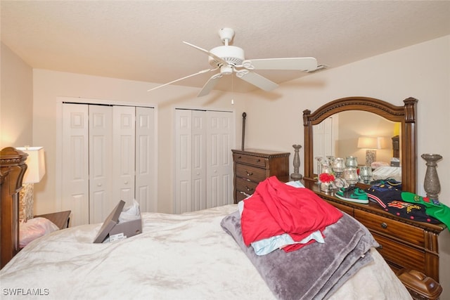 bedroom featuring a textured ceiling, multiple closets, and ceiling fan