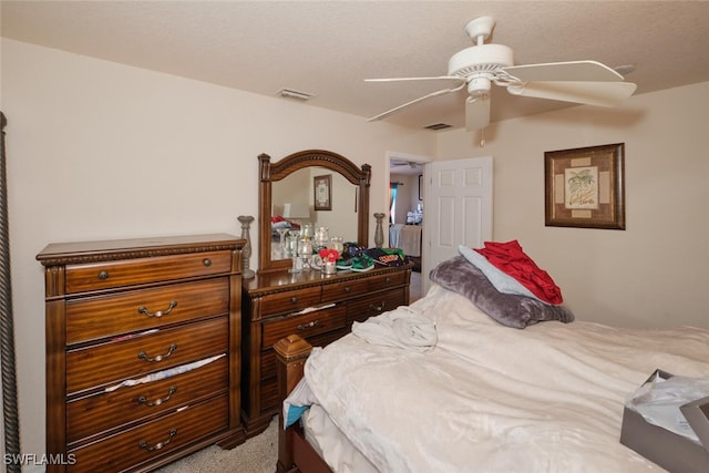 bedroom featuring light carpet, a textured ceiling, and ceiling fan