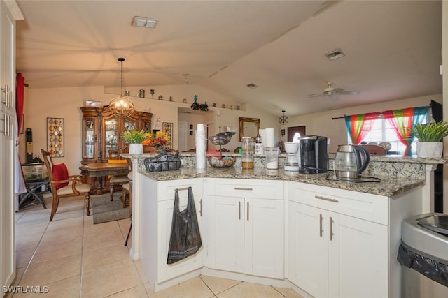 kitchen featuring lofted ceiling, light stone countertops, decorative light fixtures, white cabinetry, and ceiling fan