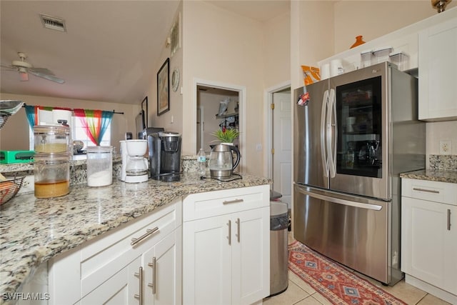 kitchen featuring stainless steel fridge, ceiling fan, light tile patterned floors, white cabinetry, and light stone counters