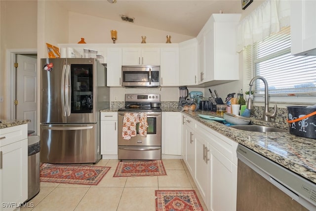 kitchen featuring lofted ceiling, sink, light tile patterned flooring, white cabinetry, and appliances with stainless steel finishes