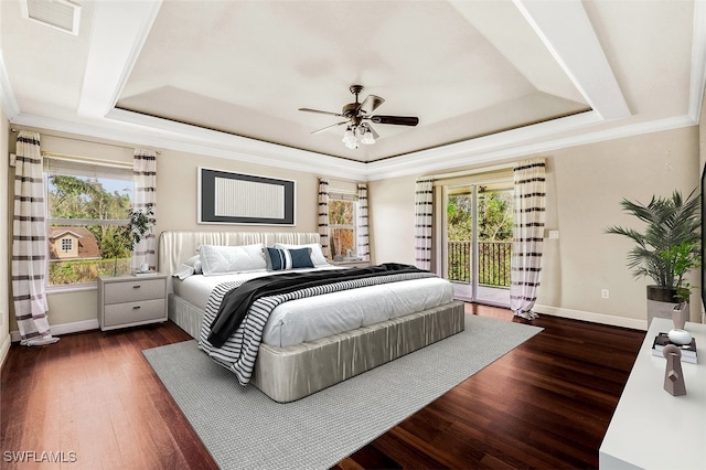 bedroom with multiple windows, access to exterior, a tray ceiling, and dark hardwood / wood-style flooring