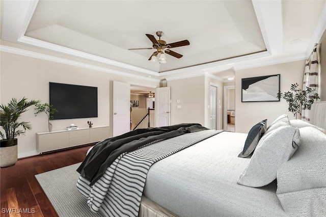 bedroom with ceiling fan, ensuite bath, a tray ceiling, and dark hardwood / wood-style floors