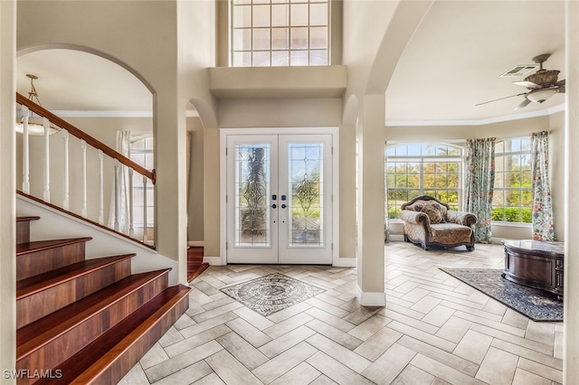 entrance foyer featuring french doors, ceiling fan, ornamental molding, and a high ceiling