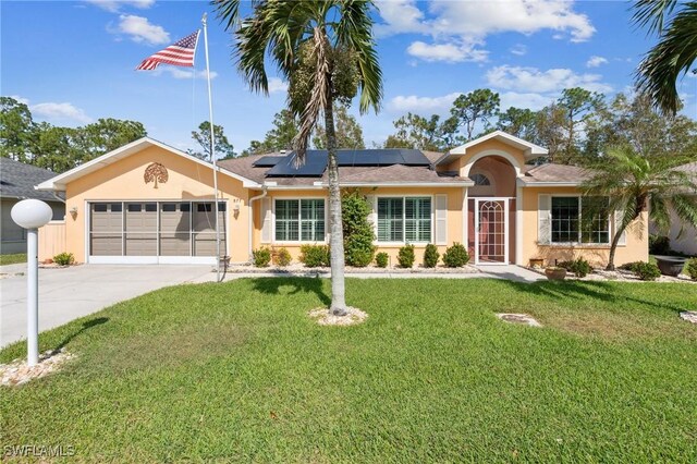 ranch-style home featuring a garage, a front yard, and solar panels