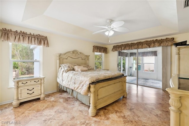 bedroom with a raised ceiling, ceiling fan, and access to exterior