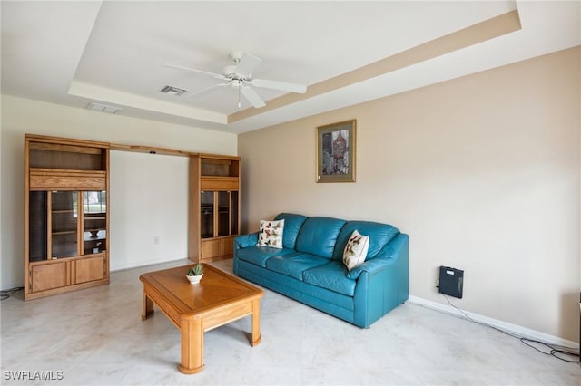 living room featuring ceiling fan and a raised ceiling