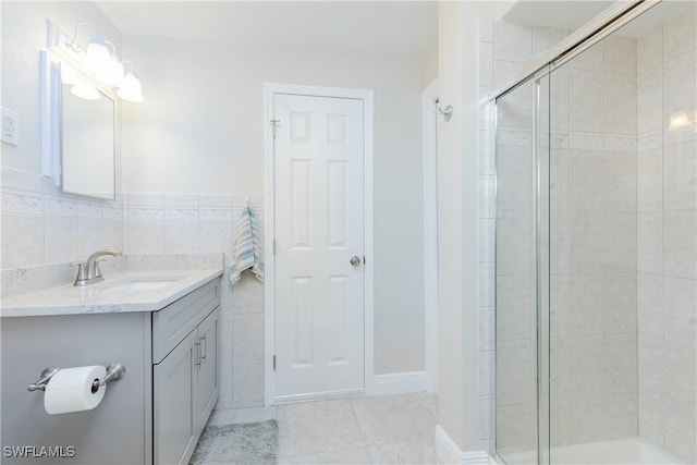 bathroom with vanity, an enclosed shower, and tile walls