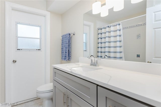 bathroom with toilet, vanity, and tile patterned floors