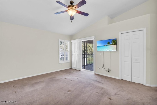 empty room with ceiling fan, vaulted ceiling, and light carpet