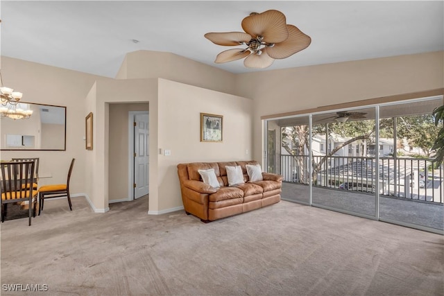 carpeted living room featuring ceiling fan with notable chandelier and vaulted ceiling