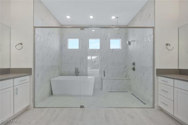 full bath featuring a stall shower, a freestanding tub, vanity, and wood finished floors