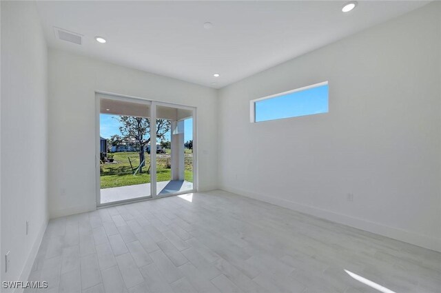 empty room featuring light wood-type flooring, visible vents, baseboards, and recessed lighting