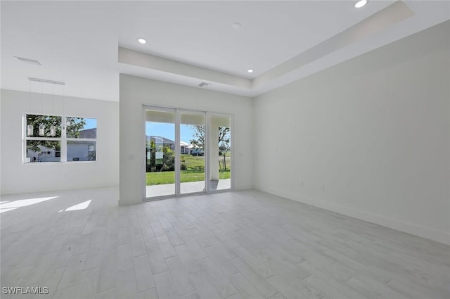 spare room with a tray ceiling, visible vents, wood finished floors, and recessed lighting