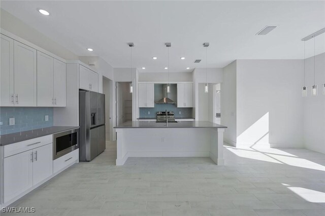 kitchen with visible vents, white cabinets, dark countertops, appliances with stainless steel finishes, and wall chimney range hood