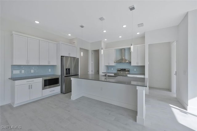 kitchen with visible vents, white cabinets, appliances with stainless steel finishes, wall chimney exhaust hood, and dark countertops