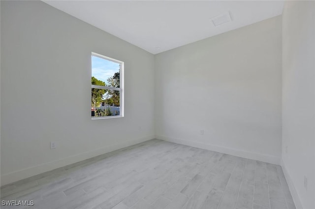 spare room featuring light wood-type flooring and baseboards