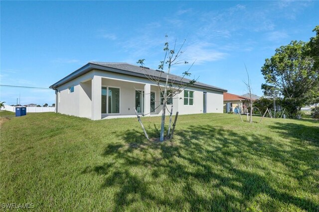 back of house with a lawn and stucco siding