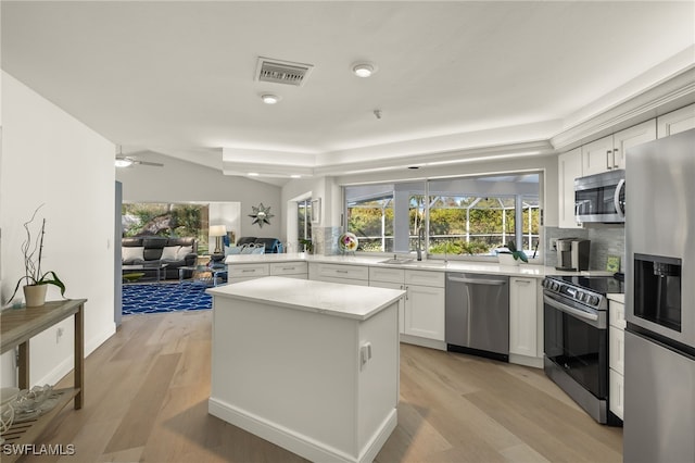 kitchen with appliances with stainless steel finishes, white cabinets, tasteful backsplash, and light hardwood / wood-style floors