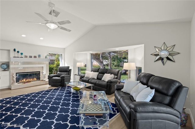 living room with hardwood / wood-style flooring, vaulted ceiling, plenty of natural light, and a fireplace