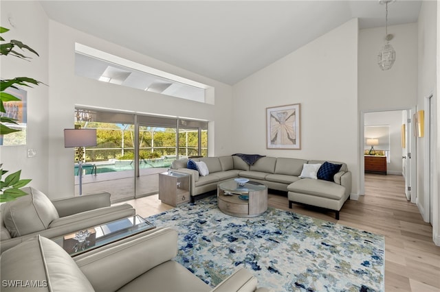 living room featuring high vaulted ceiling and light wood-type flooring