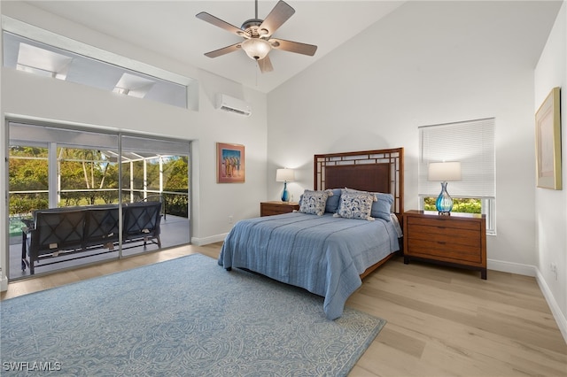 bedroom with an AC wall unit, access to exterior, multiple windows, and light wood-type flooring