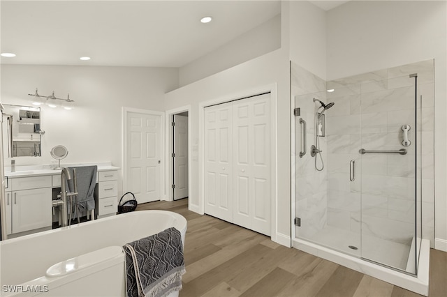 bathroom featuring vanity, hardwood / wood-style flooring, lofted ceiling, and a shower with door