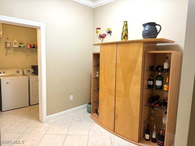 interior space with independent washer and dryer, ornamental molding, and light tile patterned floors