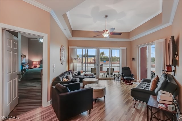 living room featuring ornamental molding, hardwood / wood-style flooring, a raised ceiling, and ceiling fan