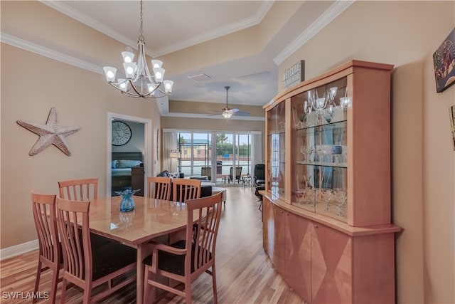 dining space with light hardwood / wood-style flooring, ornamental molding, and ceiling fan with notable chandelier