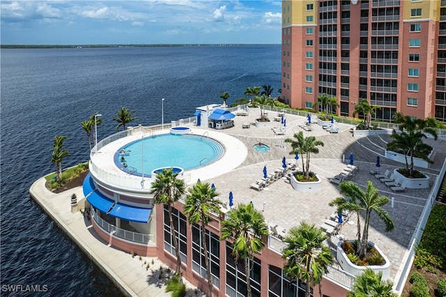 view of pool featuring a water view, a patio area, and a hot tub