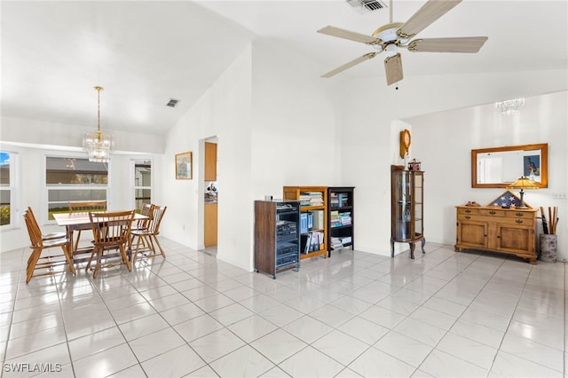 tiled dining area featuring high vaulted ceiling and ceiling fan with notable chandelier