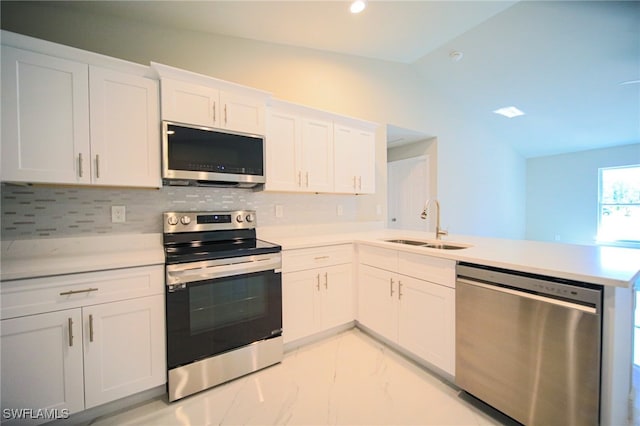 kitchen with kitchen peninsula, stainless steel appliances, sink, vaulted ceiling, and white cabinets