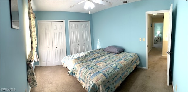 carpeted bedroom featuring ceiling fan, a textured ceiling, and multiple closets