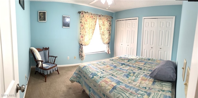 bedroom with carpet, a textured ceiling, two closets, and ceiling fan