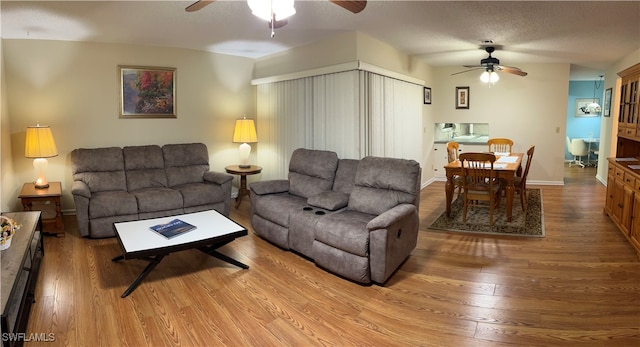 living room with ceiling fan, wood-type flooring, and a textured ceiling